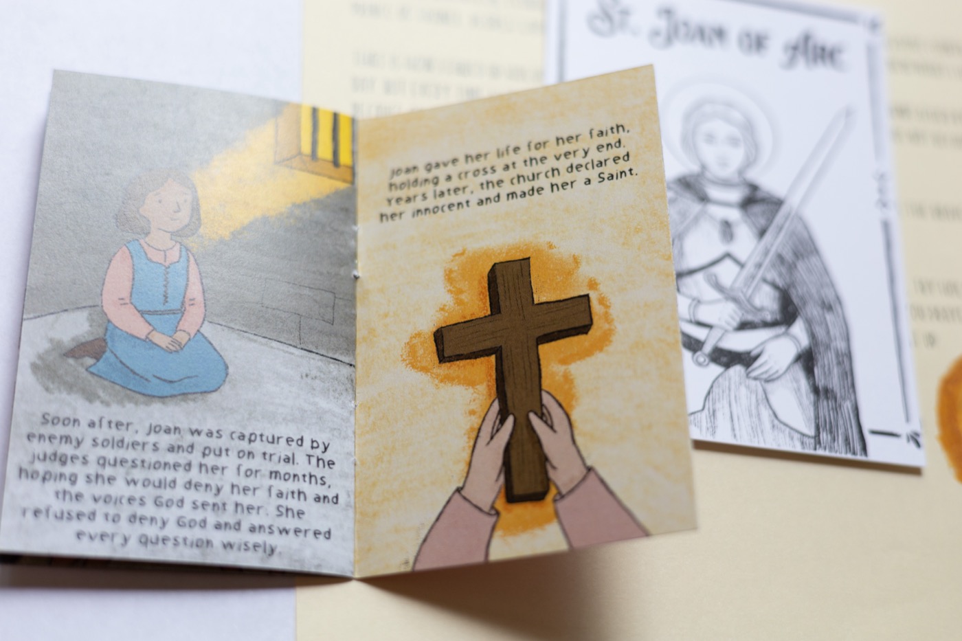 St. Joan of Arc's hand-drawn zine, open to the spread where Joan answers her judges bravely and holds a cross at the very end